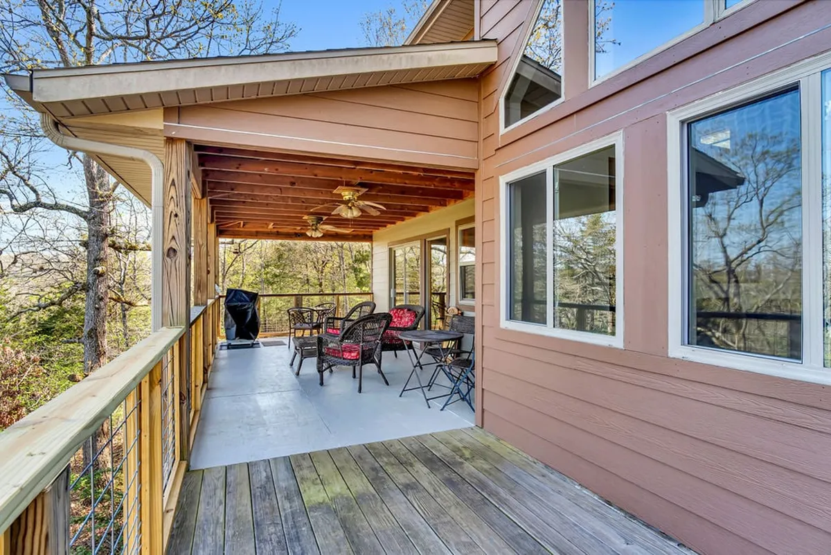 An inviting deck space with outdoor seating, a grill, and wooden railings surrounded by trees, all overlooking the lake. The setup is perfect for sunset cocktails, outdoor feasts, and savoring Ozark evenings.